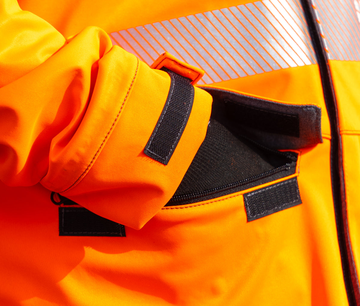 Storm cuff adjusters and zipped pocket